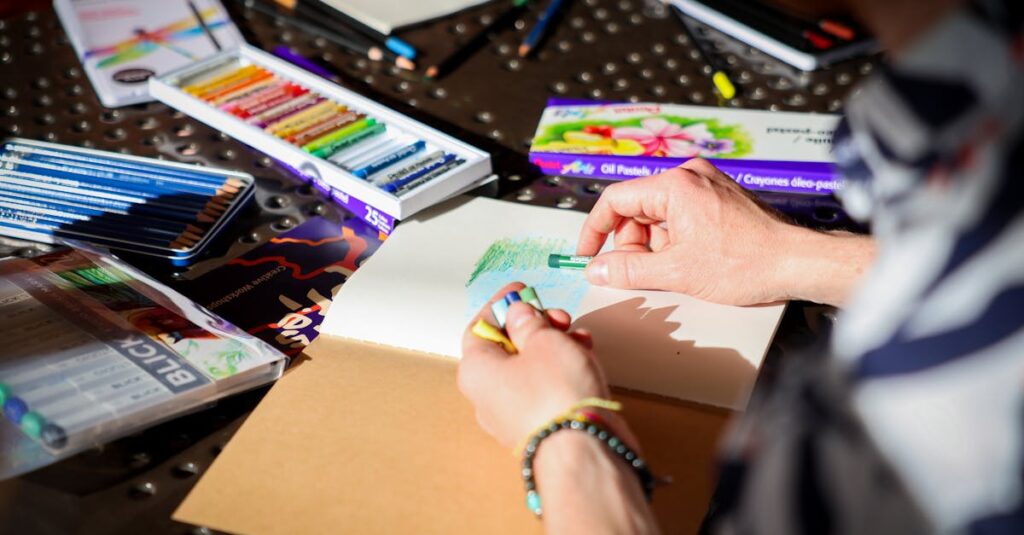 Person drawing with oil pastels in a bright, creative workspace.