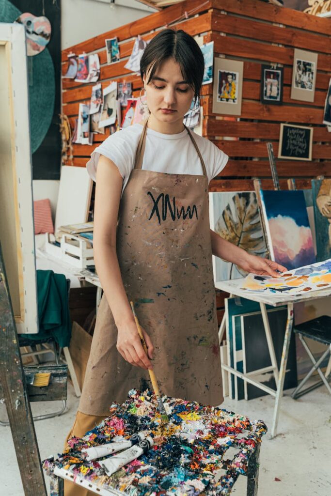 Focused artist in a vibrant studio mixing colors on a paint palette.