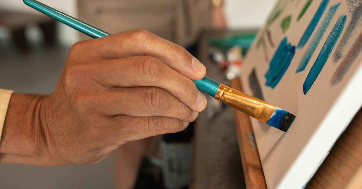 Close-up of artist's hand painting vibrant colors on canvas in studio.