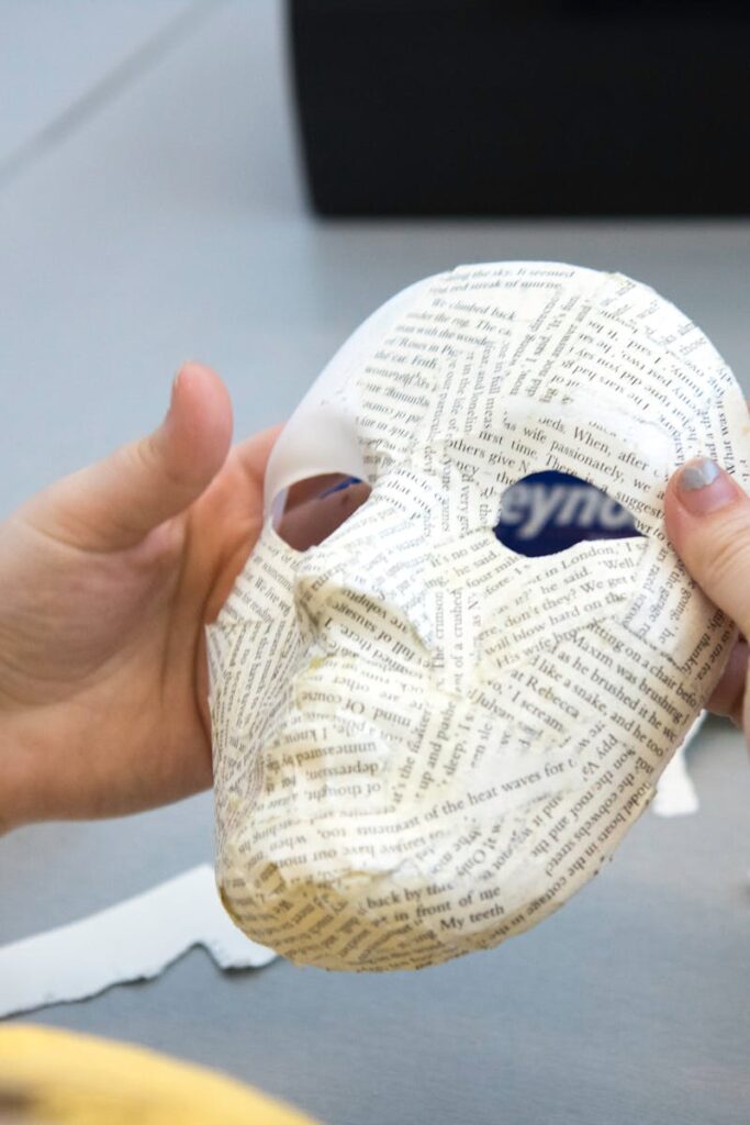 Close-up of crafting a paper mache mask during an art class project.