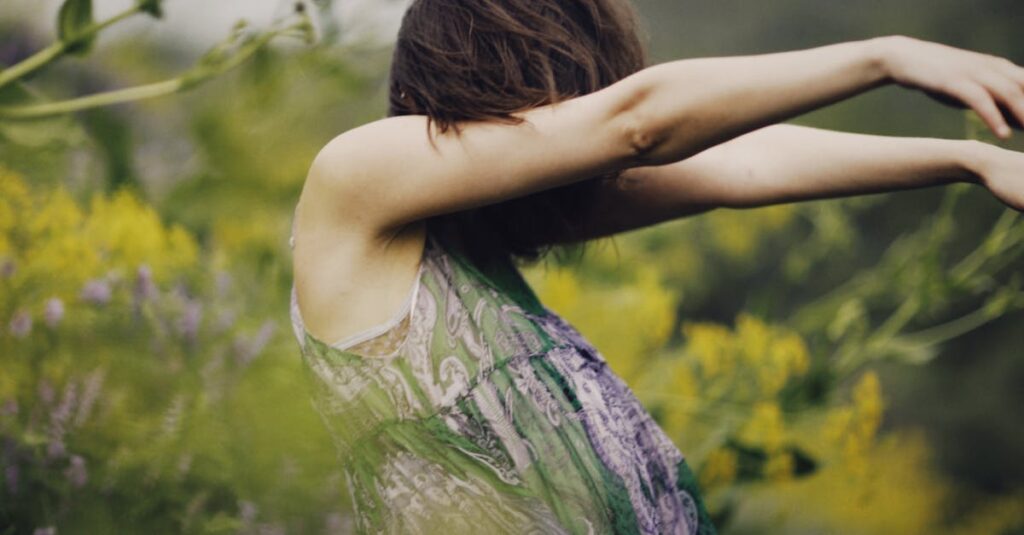 Woman dancing freely in a lush wildflower meadow, arms gracefully extended, evoking a sense of freedom.